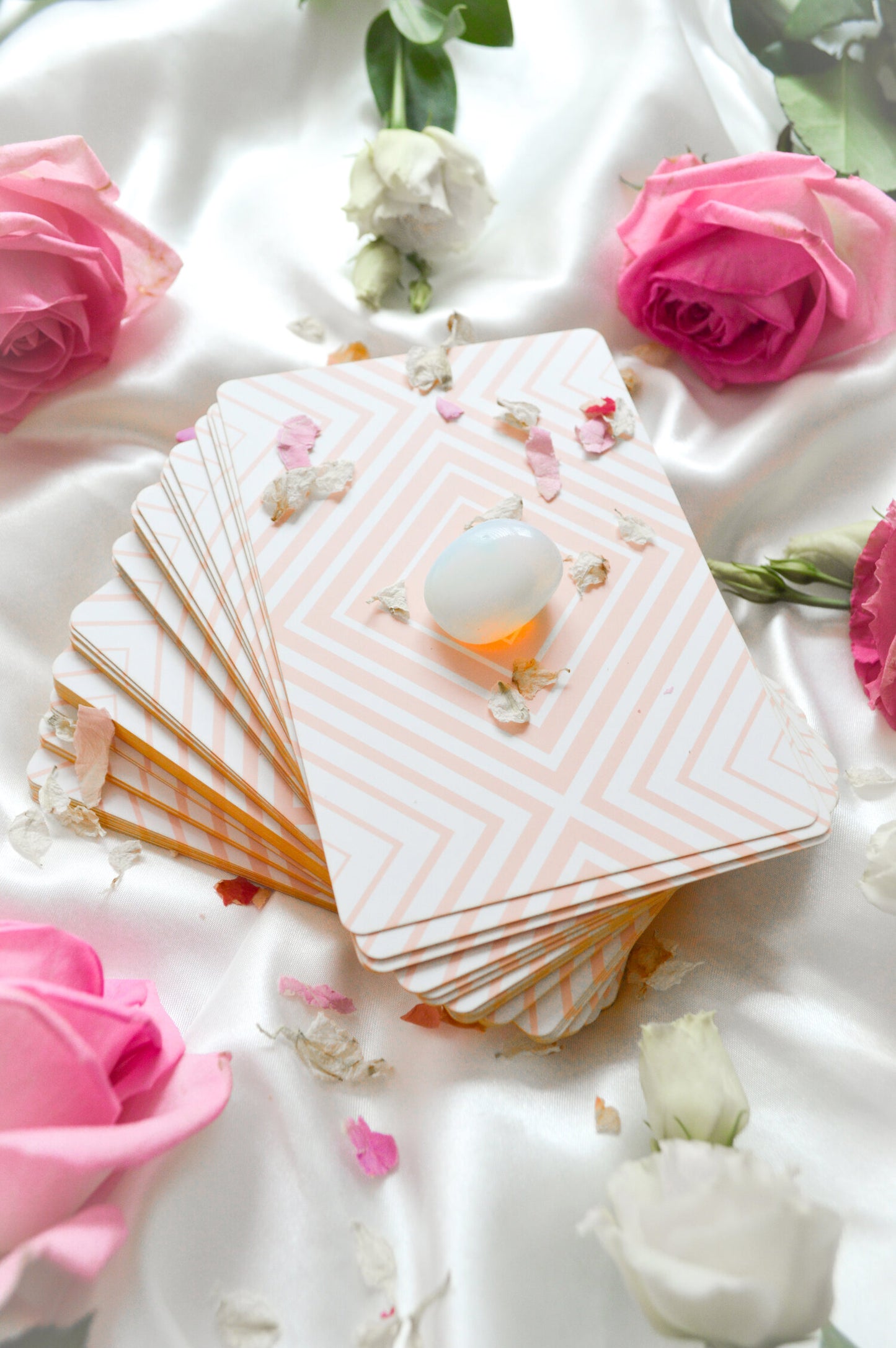 Tarot deck with tarot cards fanned out and shimmering gold edges and roses with crystal