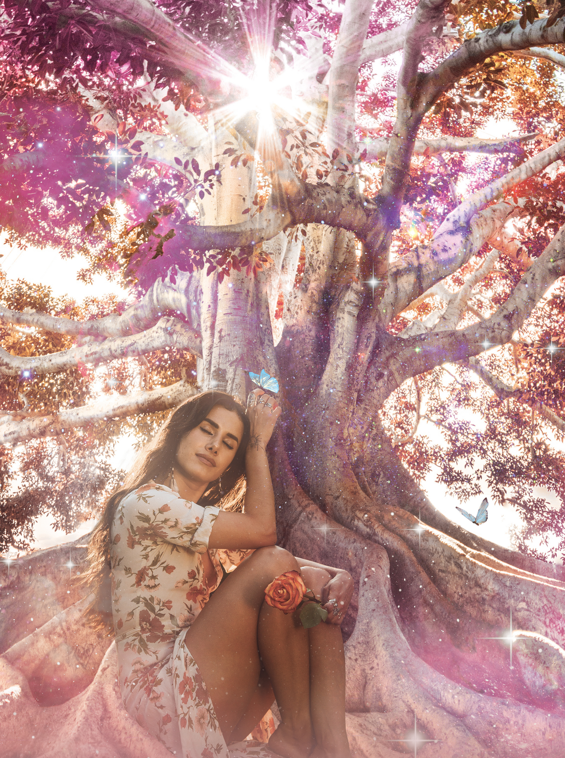 Woman named Bella Divine sitting under a large tree with a mystical, colorful background