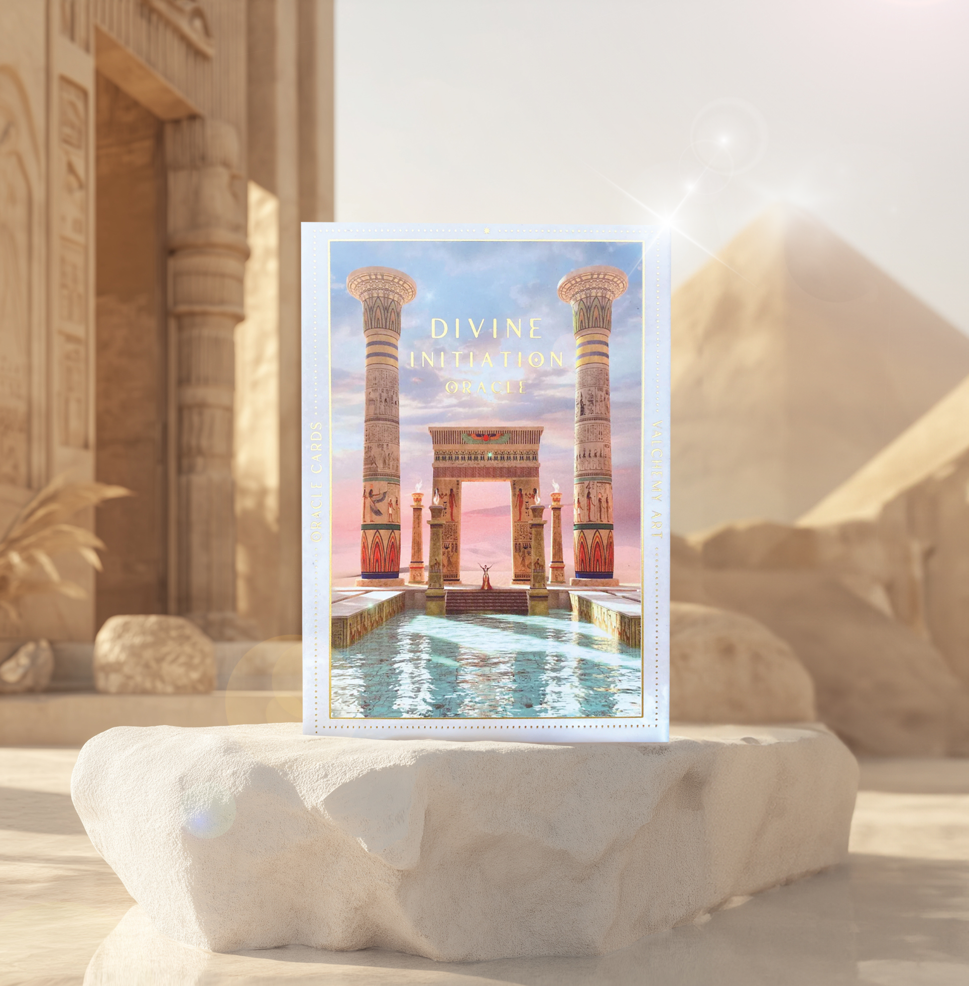 A box of the Divine Initiation Oracle Deck & Guidebook placed on a stone surface with ancient architectural imagery on the box cover, set against a backdrop suggestive of similar ancient structures.