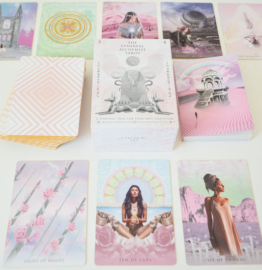 A collection of colorful tarot cards with various illustrations, including figures, animals, and abstract designs, spread out on a surface. A guidebook is also visible beside the cards.